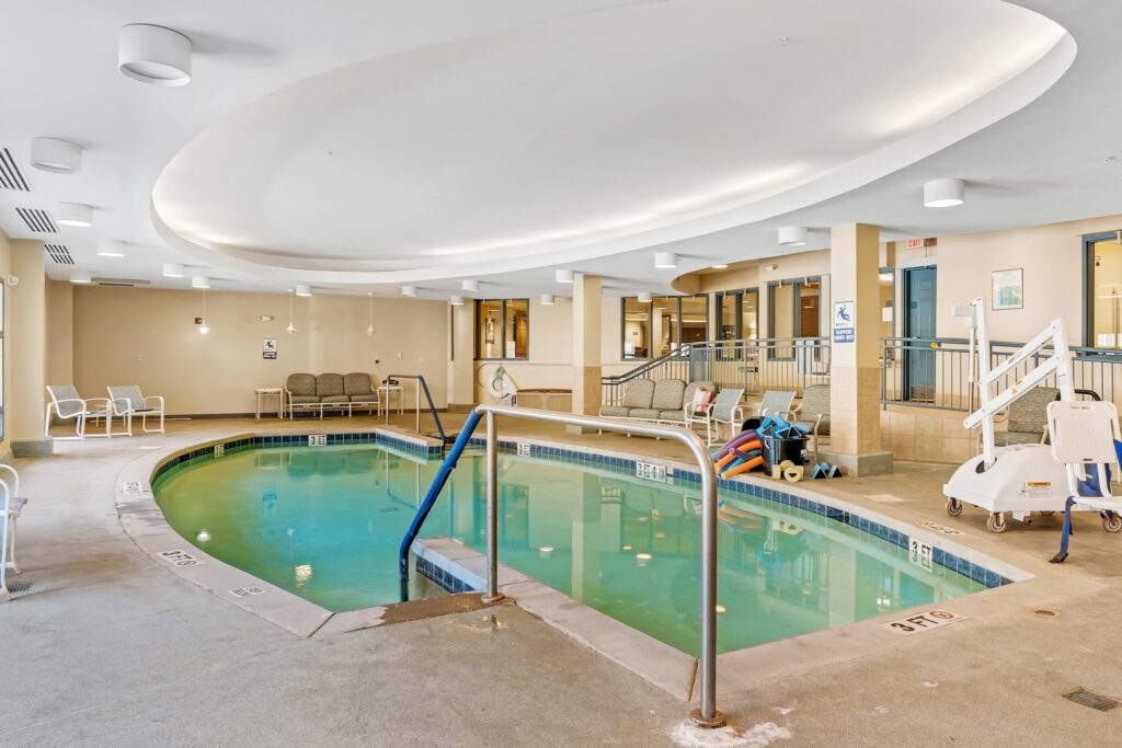 AL101282_2385_Dolly_Ridge_Vestavia_20220531_088 - Town Village Vestavia Hills An indoor pool with lounge chairs around it and a pile of colorful pool noodles.