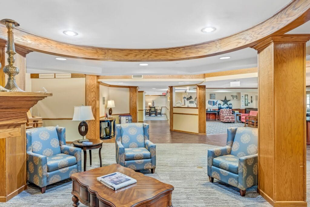 A lobby area with blue sofa chairs surrounding a brown wooden coffee table.